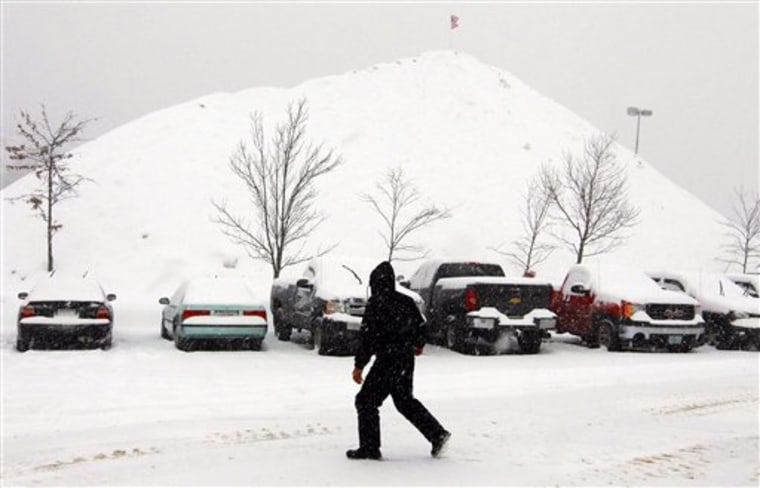 A mountain of snow towers over the back parking lot at The Loop shopping center in Methuen, Mass., on Tuesday.